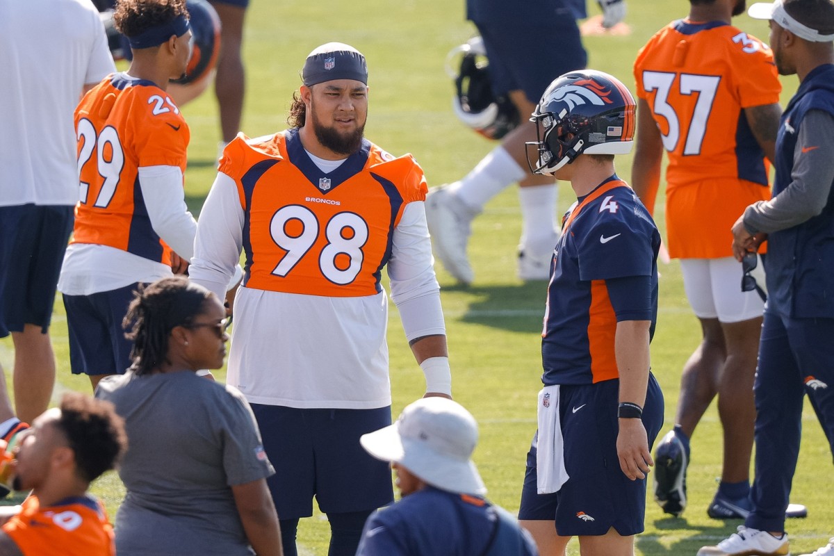 Denver Broncos defensive lineman Mike Purcell (98) talks with quarterback Brett Rypien (4) during training camp at UCHealth Training Center.