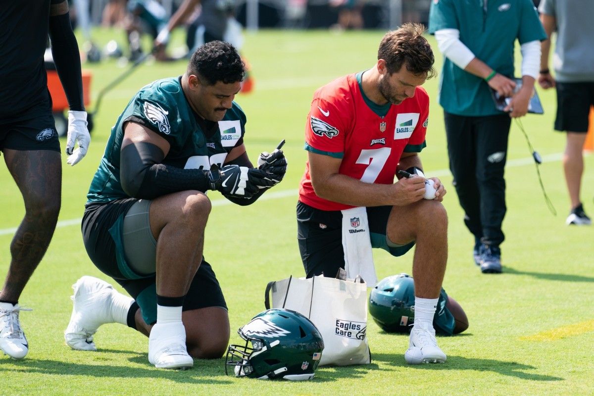 Jordan Mailata and Joe Flacco sign autographs after a recent training camp practice.