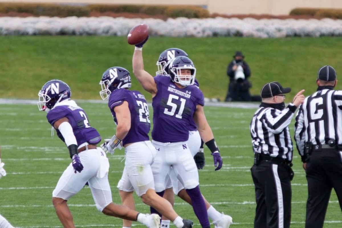 Blake Gallagher raising the ball in the air after recovering a fumble his partner in crime Paddy Fisher caused, against Wisconsin running back Garret Groshek.