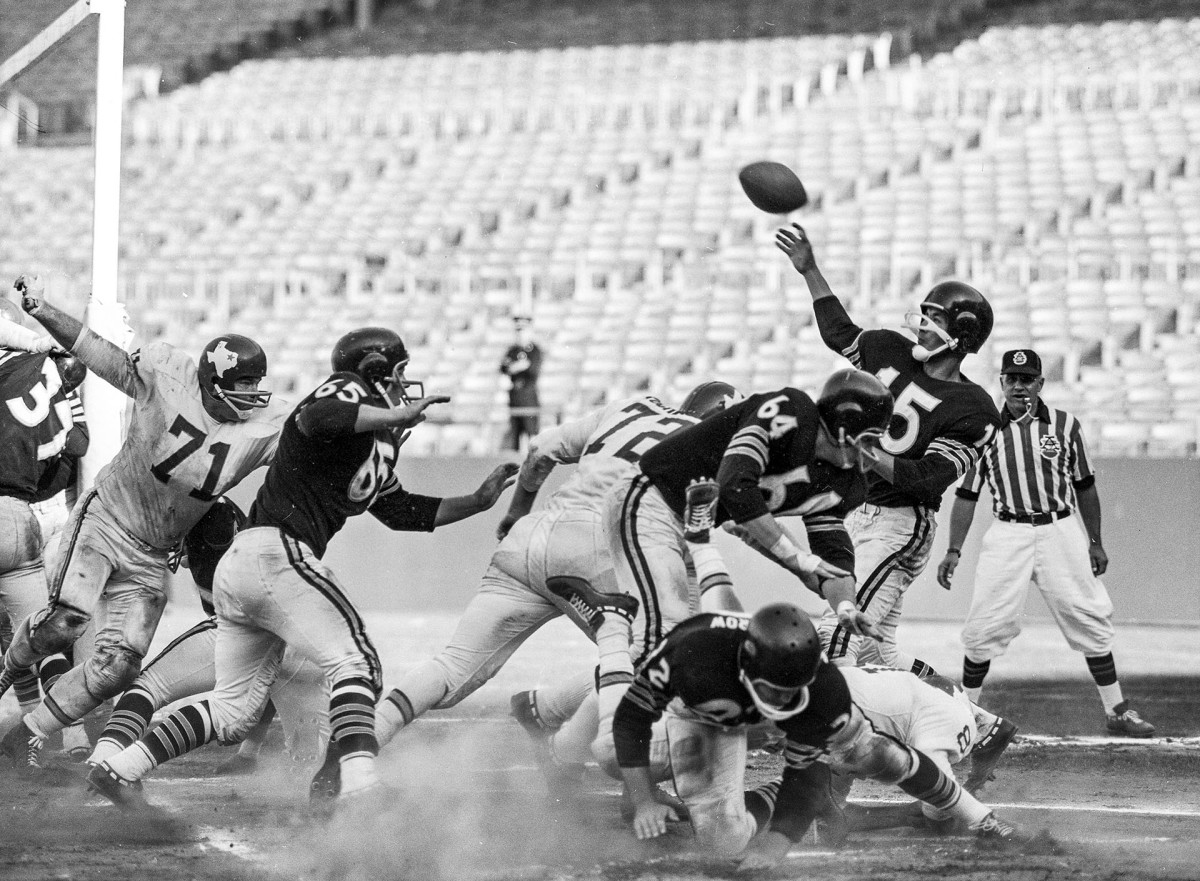 Raiders quarterback Tom Flores throws a pass as he's hit during a 1961 game against the Dallas Texans