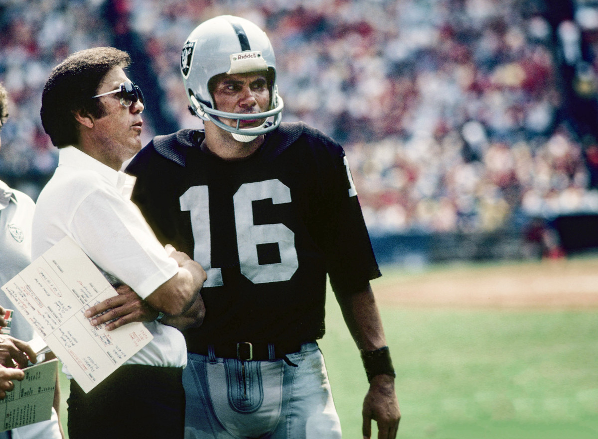 Tom Flores and Jim Plunkett talk on the sideline during a game in 1982