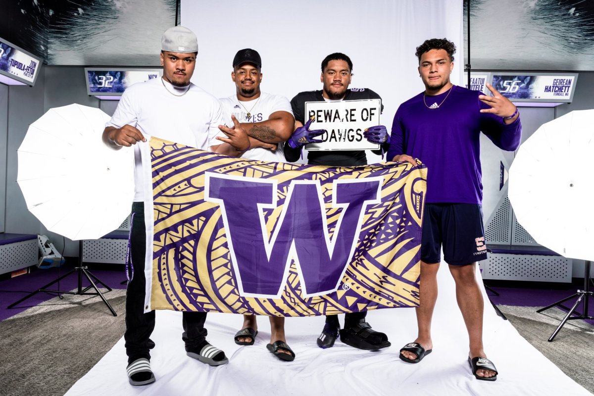 Ben Roberts, holding the sign, poses with the UW's Voi Tunuufi, Taki Taimani and Jordan Lolohea, all former East High teammates in Utah.