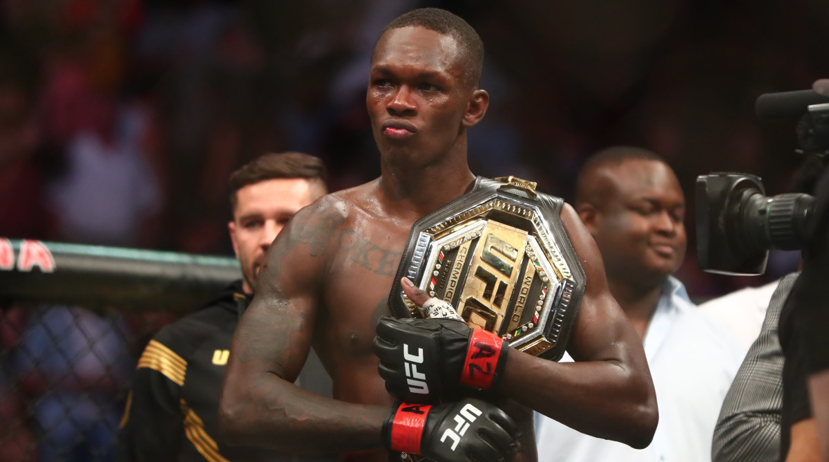 Israel Adesanya grips his UFC belt.