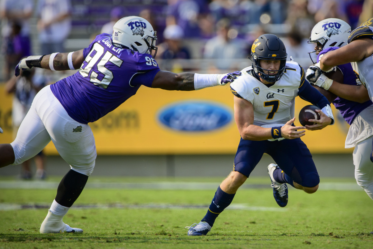 Cal quarterback Chase Garbers (7) eludes the tackle of TCU defensive tackle Terrell Cooper (95).