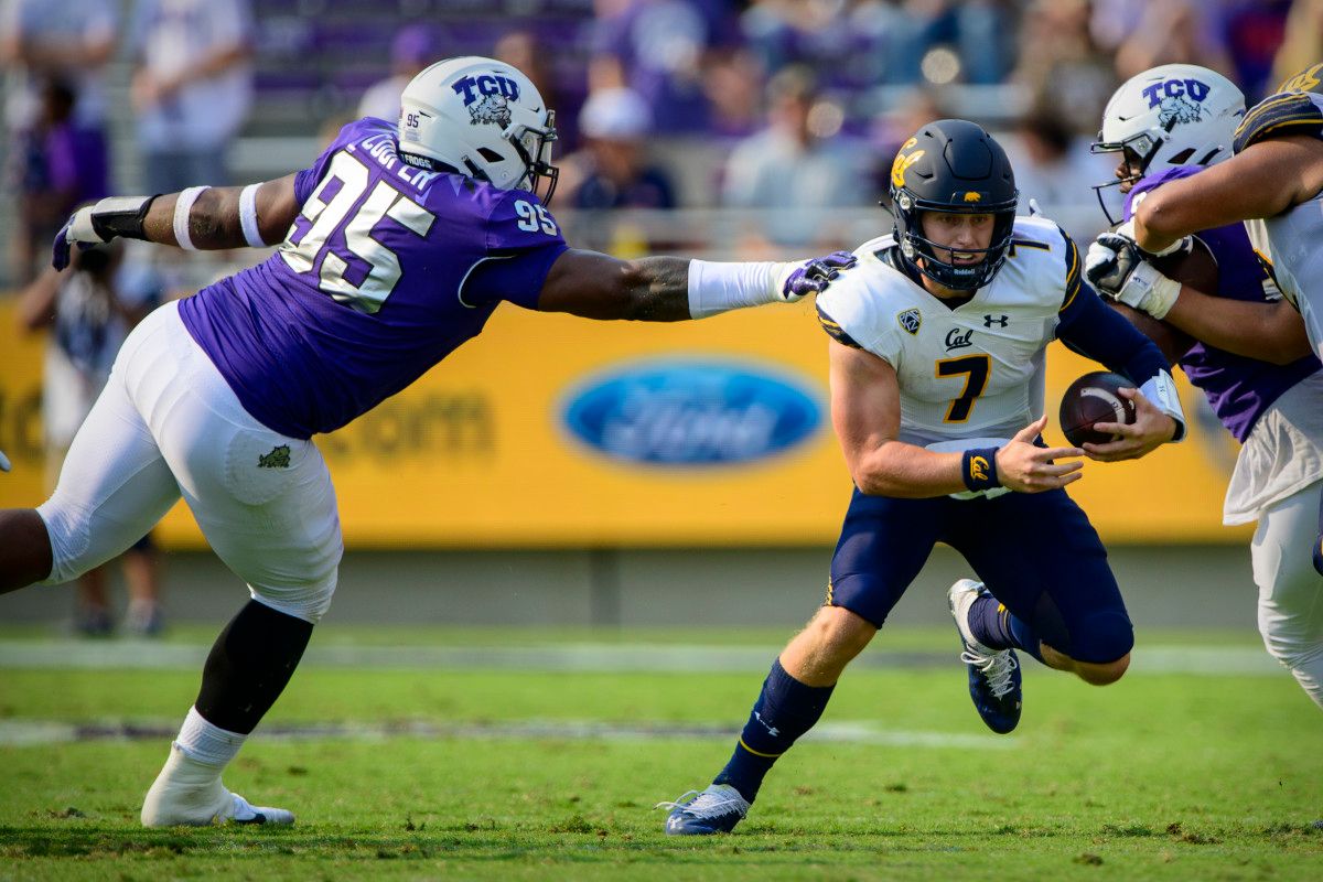 Cal quarterback Chase Garbers (7) eludes the tackle of TCU defensive tackle Terrell Cooper (95).