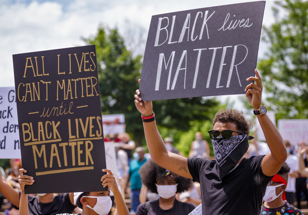 Norman native and Atlanta Hawk basketball player Trae Young, right, gathers with others protesters as they carry signs during a protest at Andrews Park on Monday, June 1, 2020.