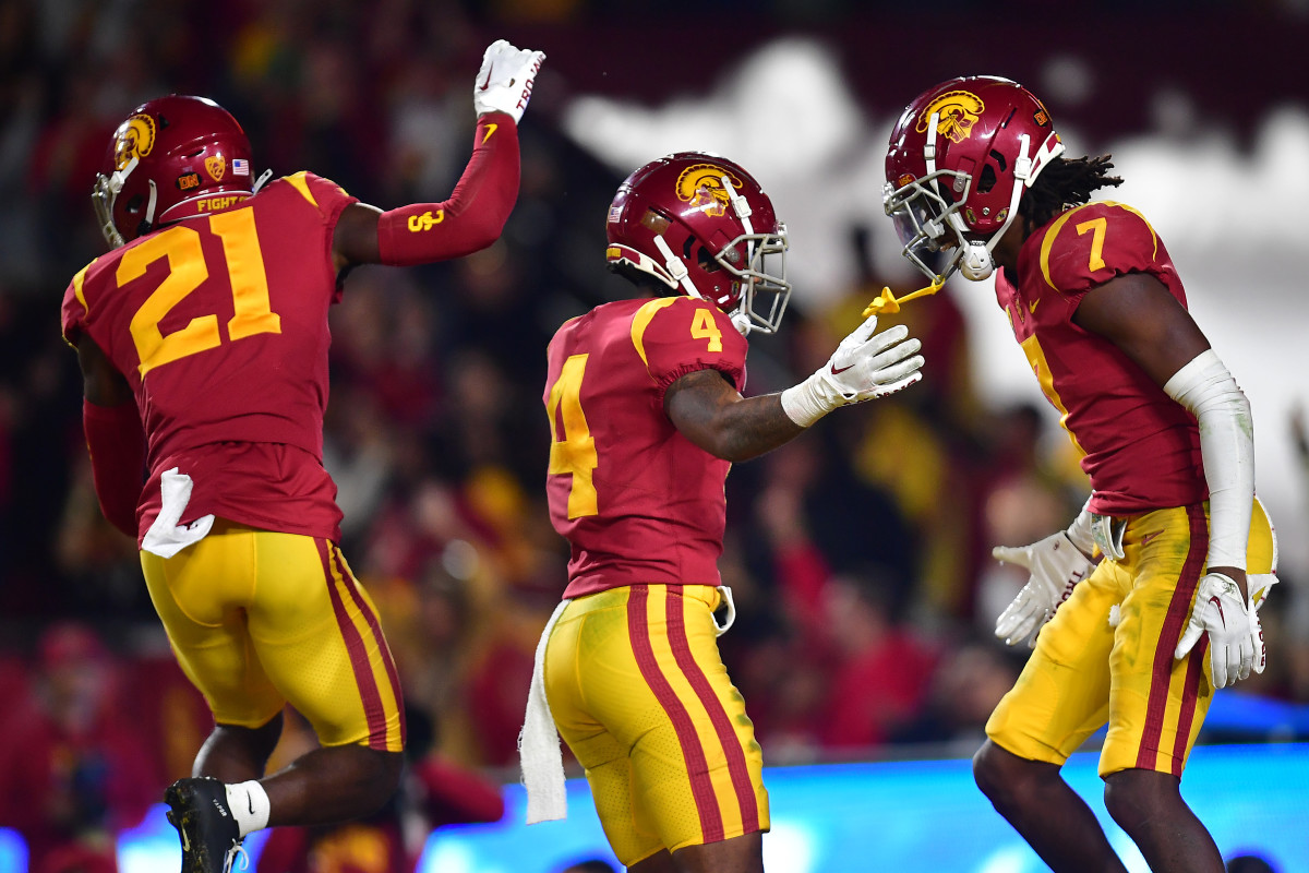 Three USC football players jump in celebration