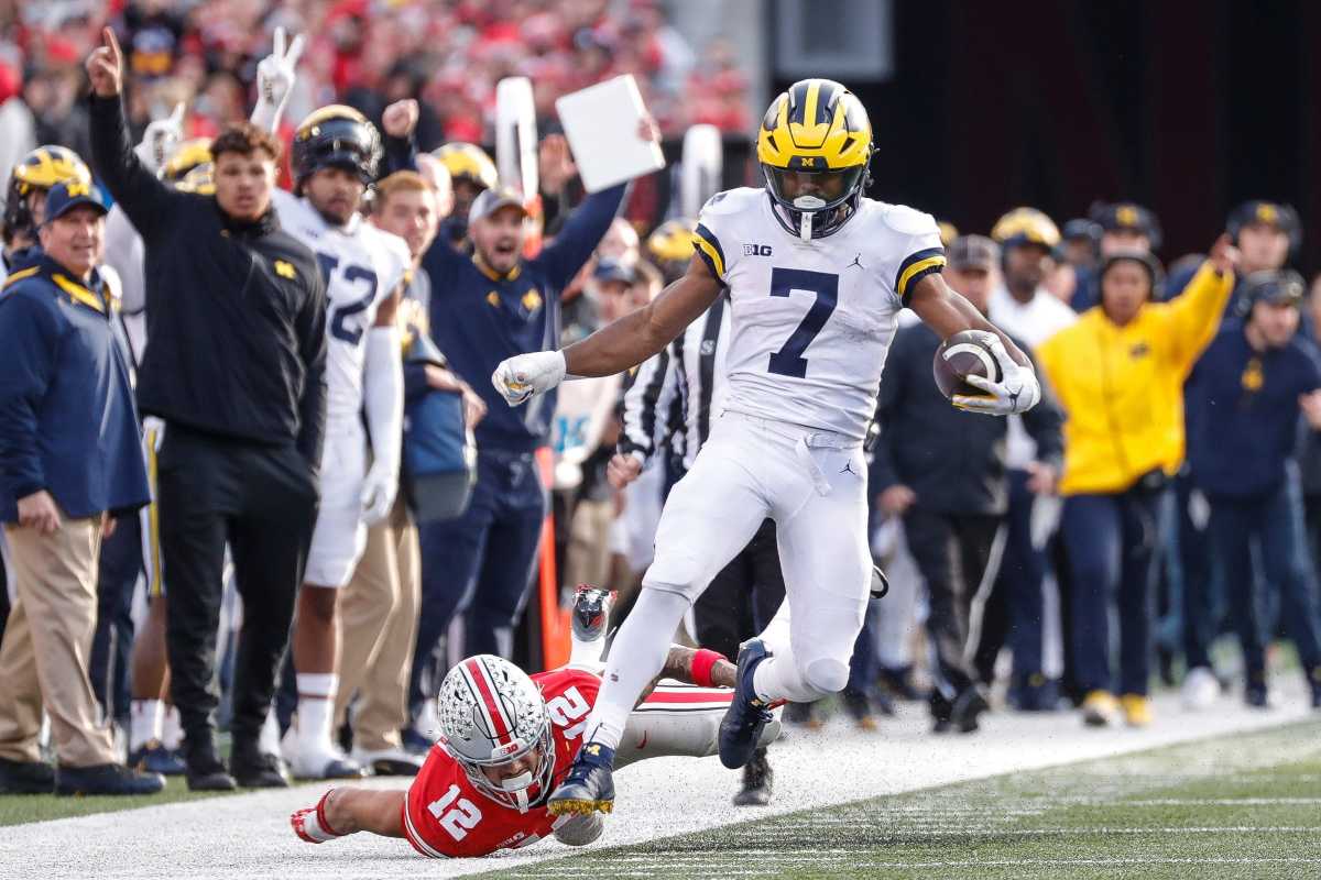 Michigan running back Donovan Edwards runs past Ohio State safety Lathan Ransom, who is on the ground behind him