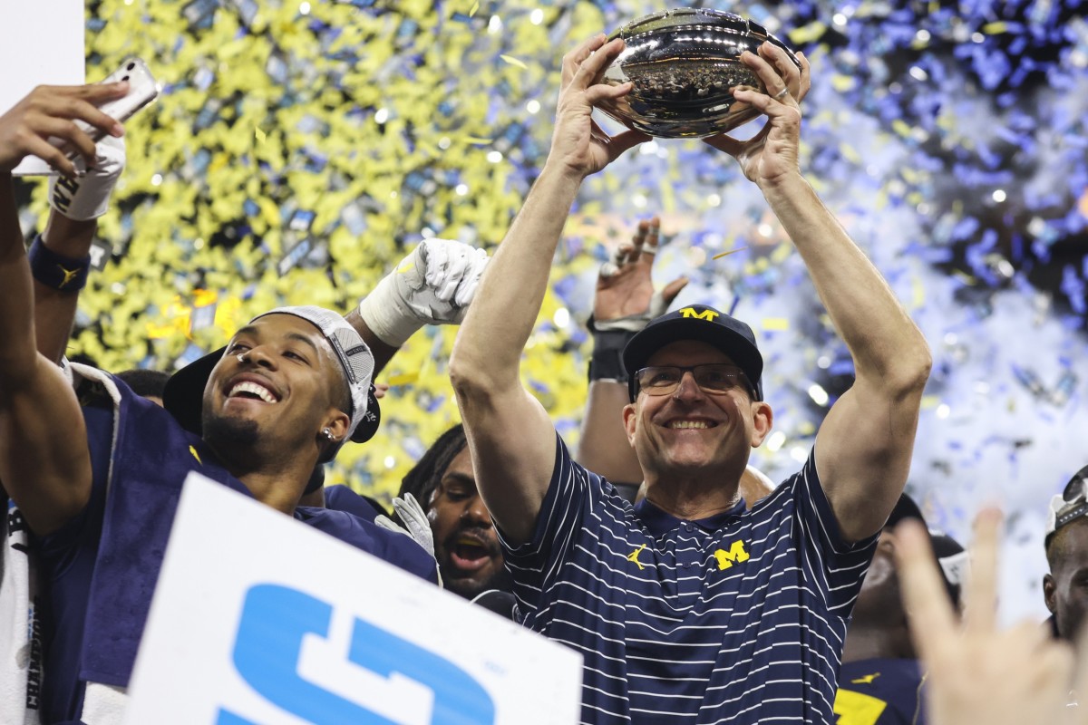 Michigan Wolverines head coach Jim Harbaugh raises the championship trophy following their 43-22 victory against Purdue in the Big Ten Championship at Lucas Oil Stadium.