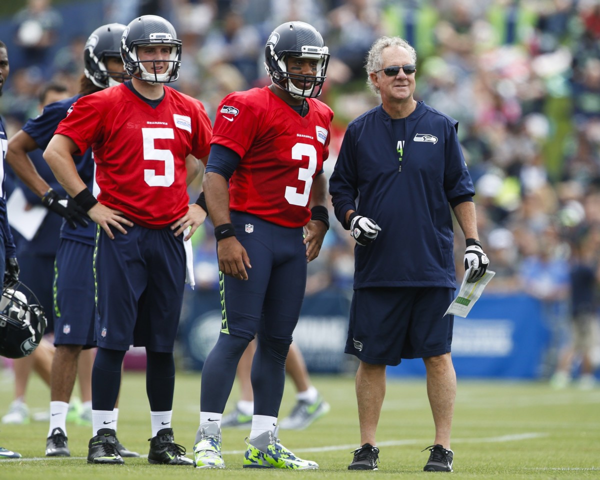 Seattle Seahawks quarterback Jake Heaps (5) and quarterback Russell Wilson (3) and quarterbacks coach Carl Smith watch a drill during training camp at the Virginia Mason Athletic Center.