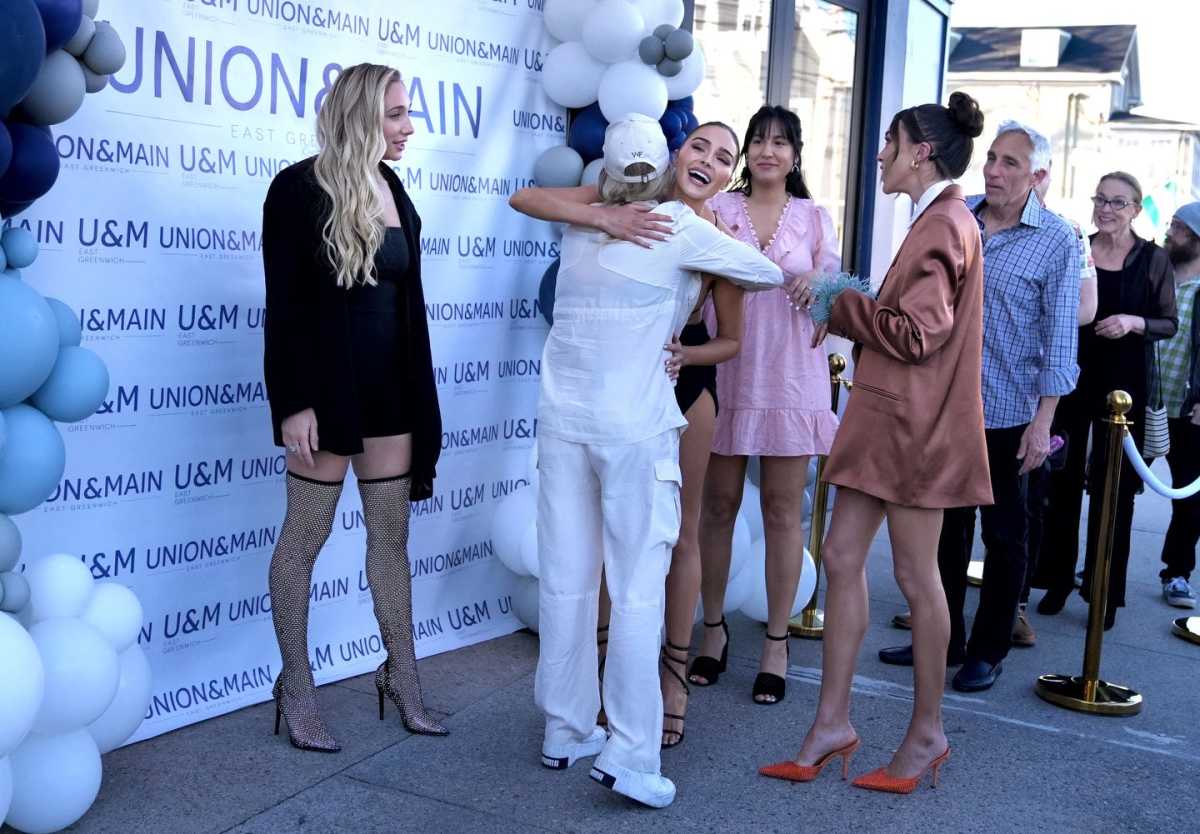 Olivia Culpo hugs someone as sisters Aurora and Sophie stand at a restaurant opening