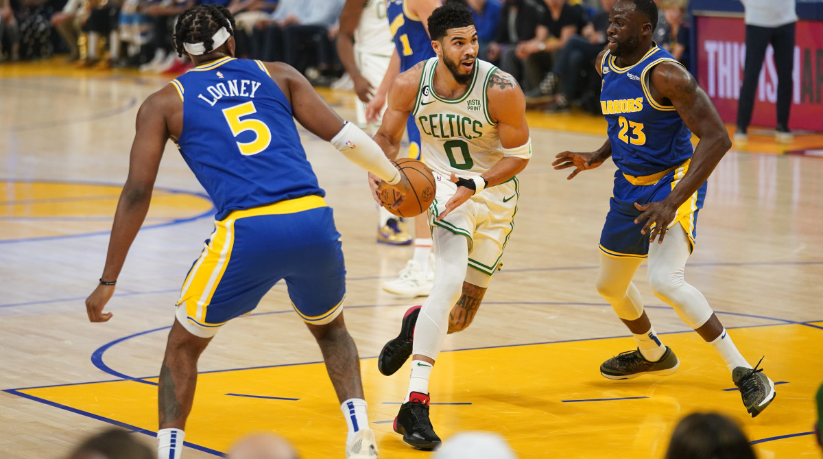 Celtics wing Jayson Tatum drives vs. Warriors forward Draymond Green.