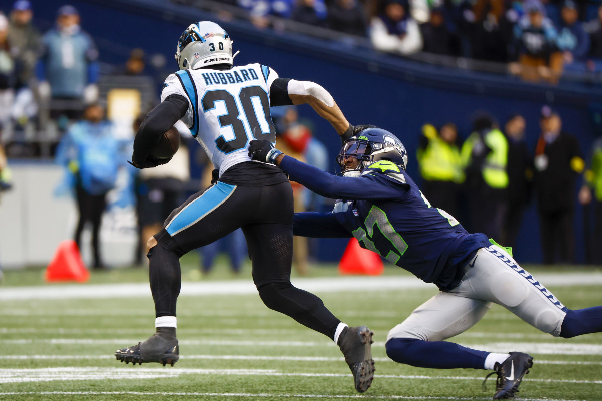 Carolina Panthers running back Chuba Hubbard (30) stiff arms a way from a tackle attempt by Seattle Seahawks cornerback Tariq Woolen (27) during the fourth quarter at Lumen Field.