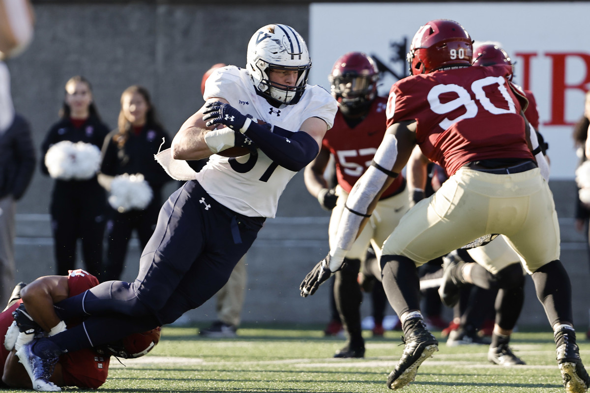 BOSTON, MA - NOVEMBER 19: Jackson Hawes #87 of the Yale Bulldogs secures the ball while being tackled in the second half against the Harvard Crimson at Harvard Stadium on November 19, 2022 in Boston, Massachusetts.