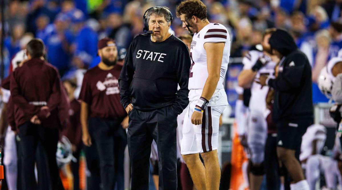 Mississippi State head coach Mike Leach and quarterback Will Rogers talk in between plays during a game.