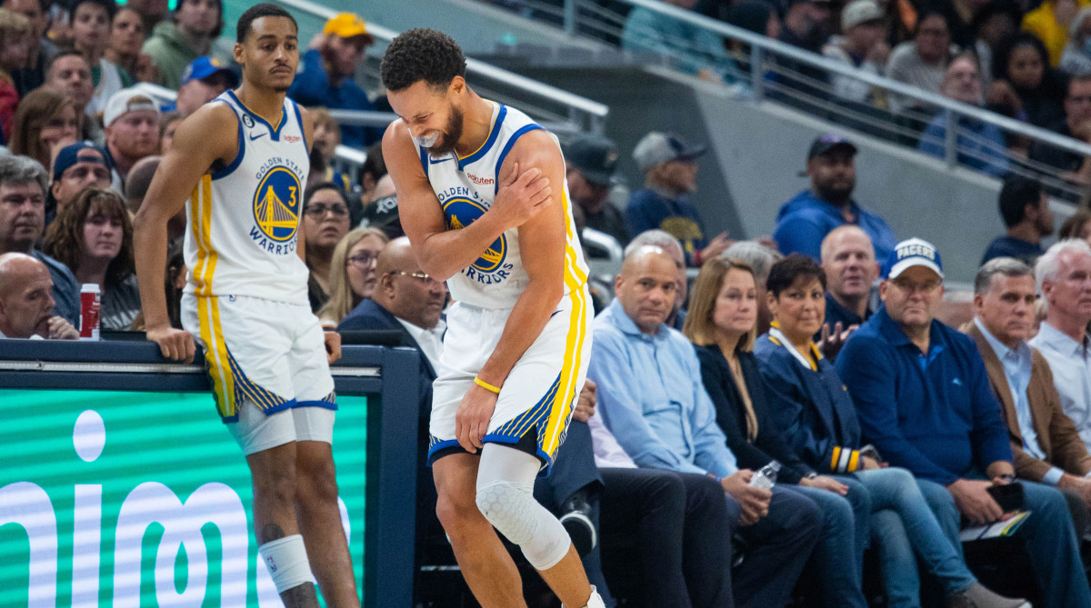 Warriors guard Stephen Curry grabs his shoulder after suffering an injury.