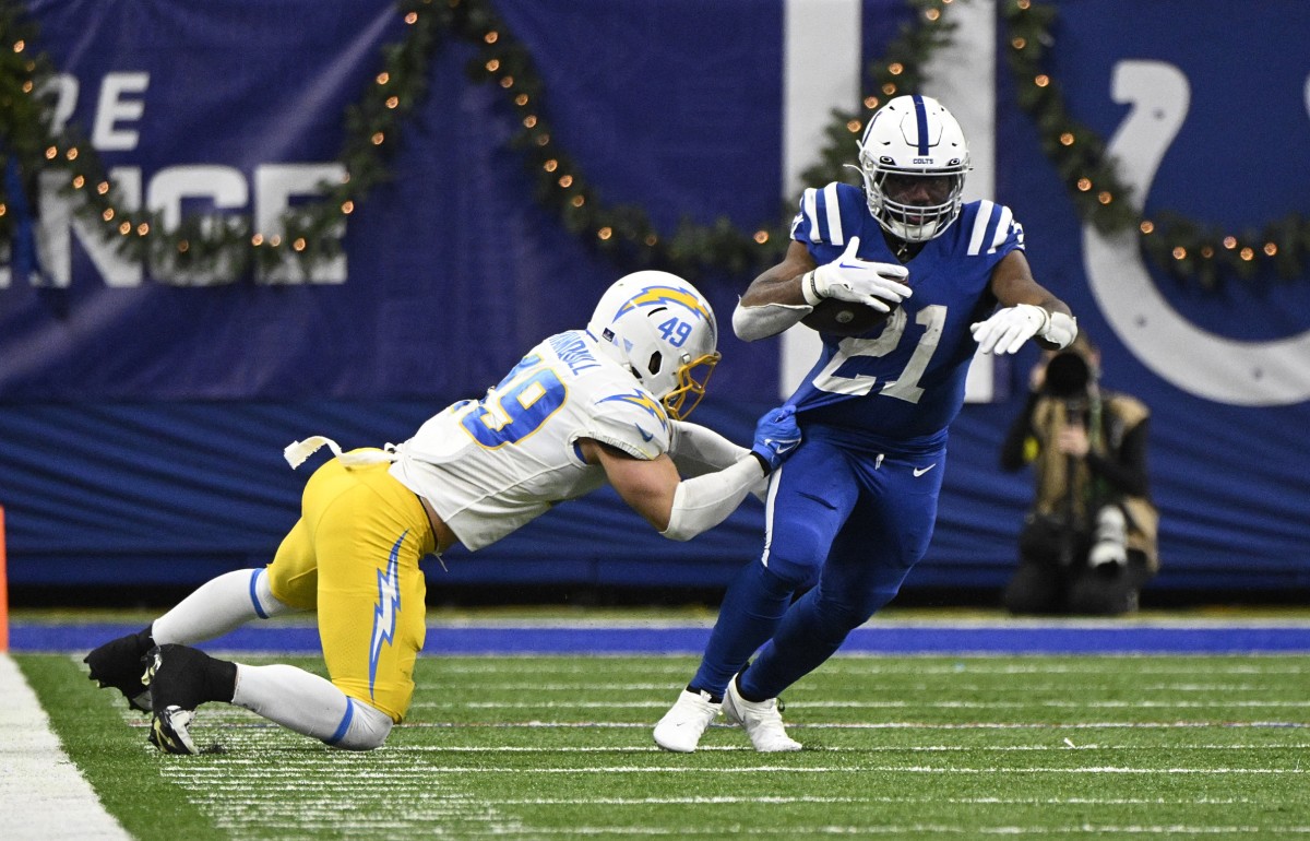Dec 26, 2022; Indianapolis, Indiana, USA; Indianapolis Colts running back Zack Moss (21) evades tackle by Los Angeles Chargers linebacker Drue Tranquill (49) during the second half at Lucas Oil Stadium.