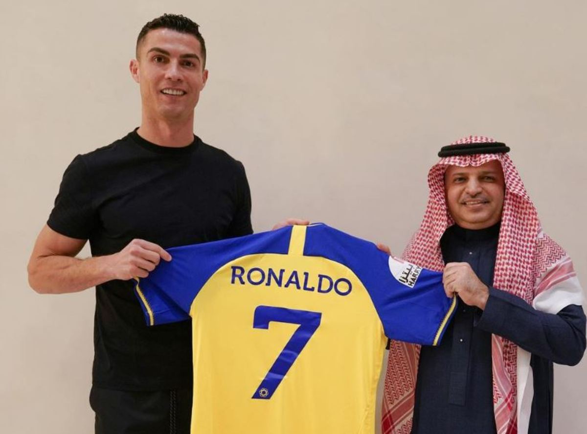 Cristiano Ronaldo pictured (left) holding an Al Nassr jersey after signing for the Saudi Pro League club on a free transfer