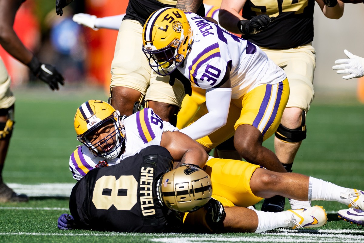 LSU Tigers defensive lineman Mekhi Wingo (92) and LSU Tigers linebacker Greg Penn III (30) tackle Purdue Boilermakers wide receiver TJ Sheffield (8) during the first half at Camping World Stadium.
