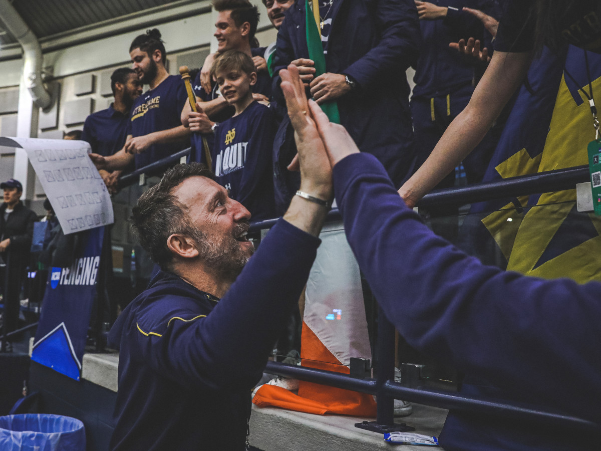 Notre Dame fencing coach Gia Kvaratskhelia high-fives fans.