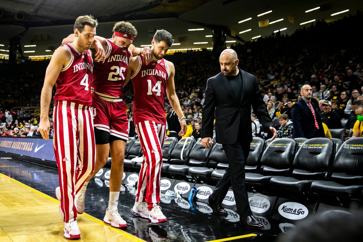 Indiana forward Race Thompson (25) gets helped off the floor by teammates Michael Shipp, left, and Nathan Childress after getting injured as Clif Marshall, director of athletic performance, right, looks on during a NCAA Big Ten Conference men's basketball game against Iowa.