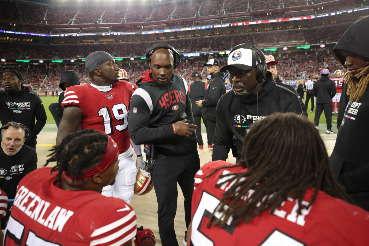 DeMeco Ryans and Johnny Holland talk to the 49ers linebackers on the sideline during a game
