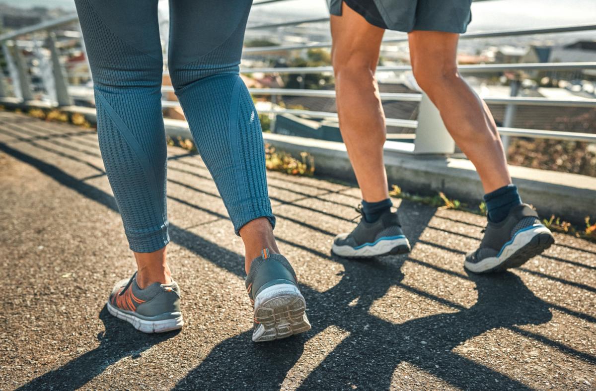 The legs and feet of a man and woman running on pavement