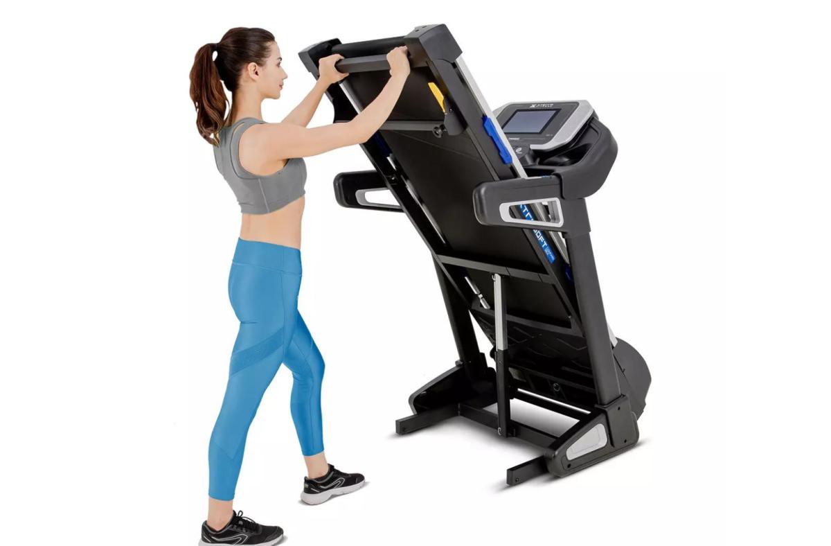 A woman vertically folding the XTERRA TRX5500 treadmill for storage