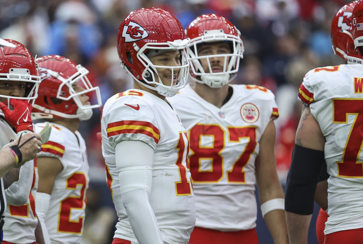 Patrick Mahomes smiles while looking to the sideline from the huddle during a game in December