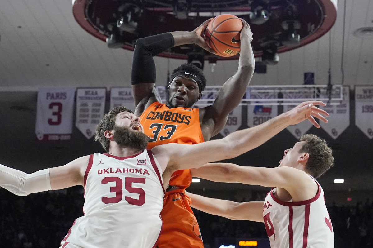 Oklahoma State forward Moussa Cisse (33) grabs a rebound above Oklahoma forward Tanner Groves (35) and forward Jacob Groves, right, in the first half of an NCAA college basketball game Wednesday, Feb. 1, 2023, in Norman, Okla.