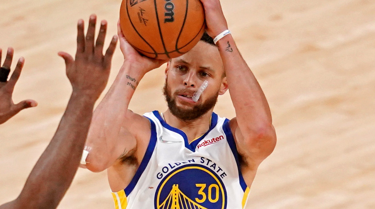 Warriors guard Steph Curry shoots a contested shot with his mouthpiece hanging out