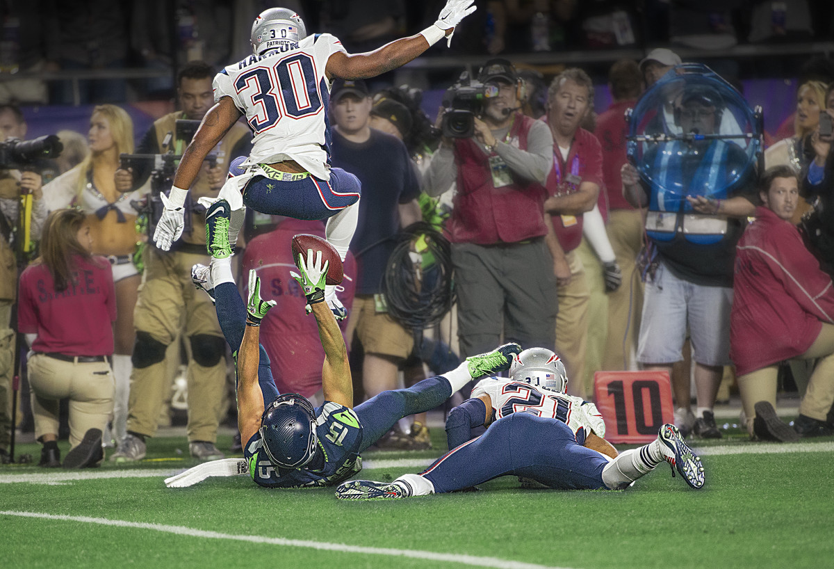 On his back, Jermaine Kearse reaches for a catch between two Patriots defenders during the fourth quarter of Super Bowl 49