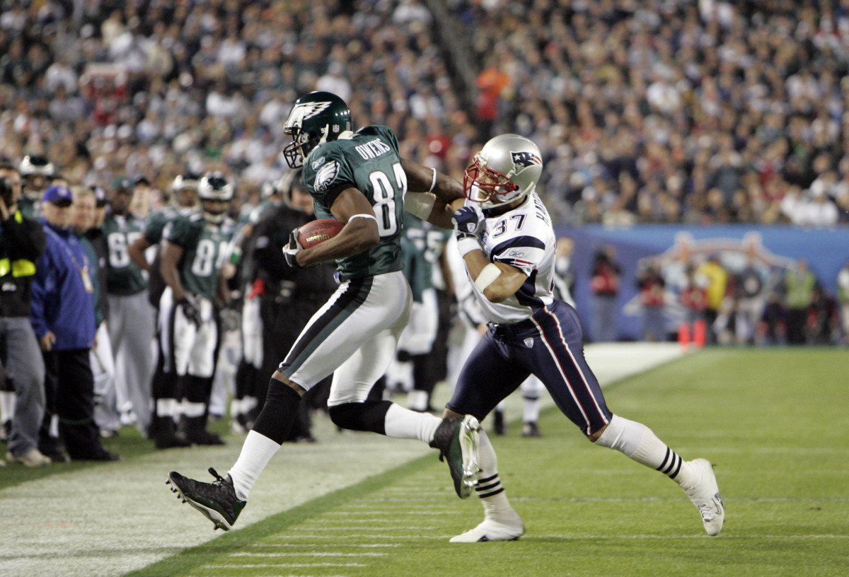 Philadelphia Eagles receiver Terrell Owens runs with the ball as New England Patriots defensive back Rodney Harrison approaches to try to tackle him