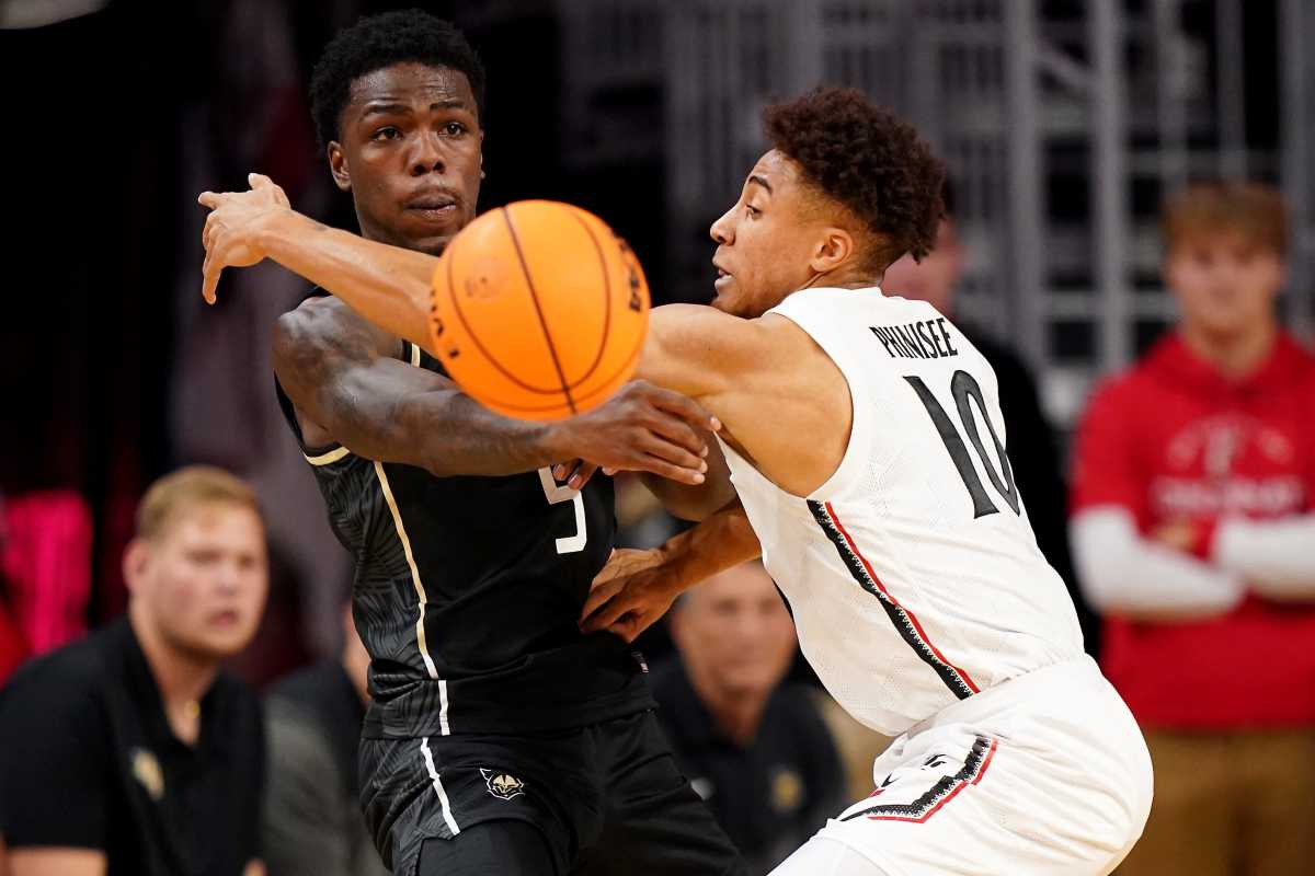 UCF Knights guard P.J. Edwards (5) passes as Cincinnati Bearcats guard Rob Phinisee (10) defends in the second half of a college basketball game between the UCF Knights and the Cincinnati Bearcats, Saturday, Feb. 4, 2023, at Fifth Third Arena in Cincinnati. The Cincinnati Bearcats won, 73-64. Ucf Knights At Cincinnati Bearcats Feb 4 0353