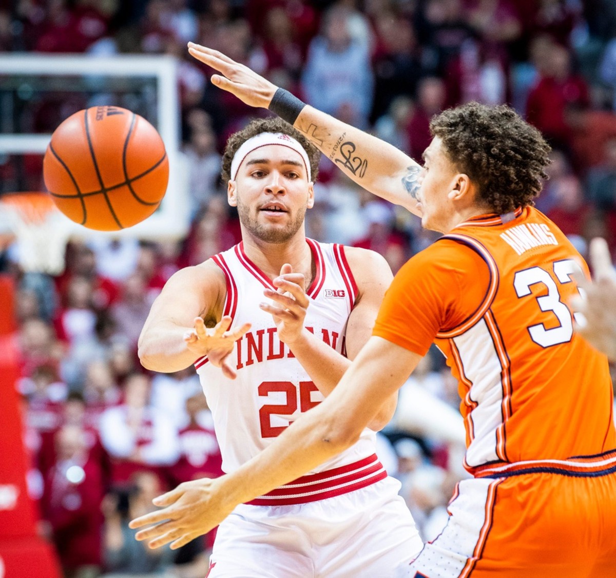 Indiana's Race Thompson (25) passes through the arms of Illinois' Coleman Hawkins (33) during the first half of the Indiana versus Illinois men's basketball game.