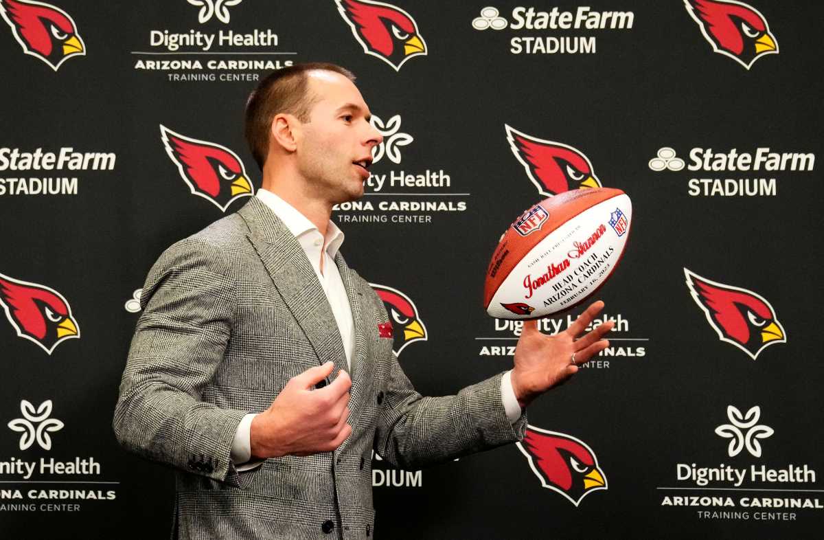 Jonathan Gannon tosses a football in the air during his introductory press conference