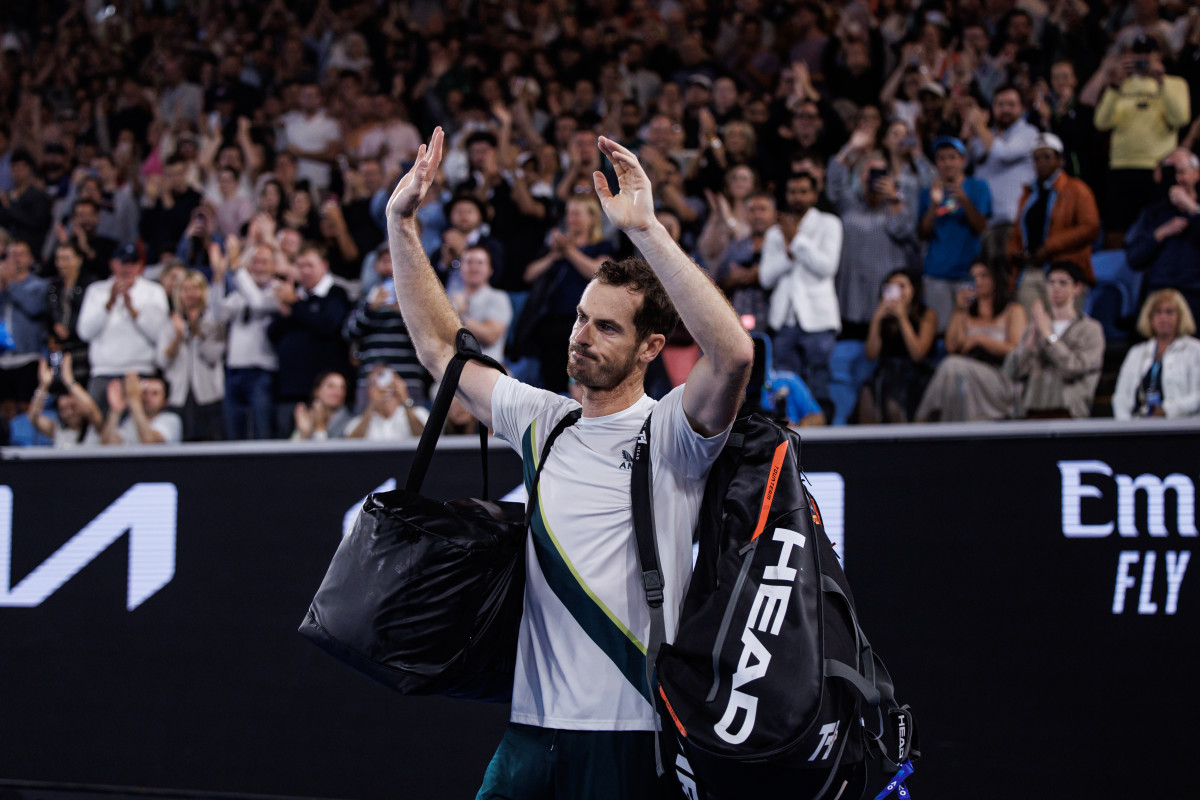 Andy Murray waves to the crowd holding his tennis bags as he walks off the court