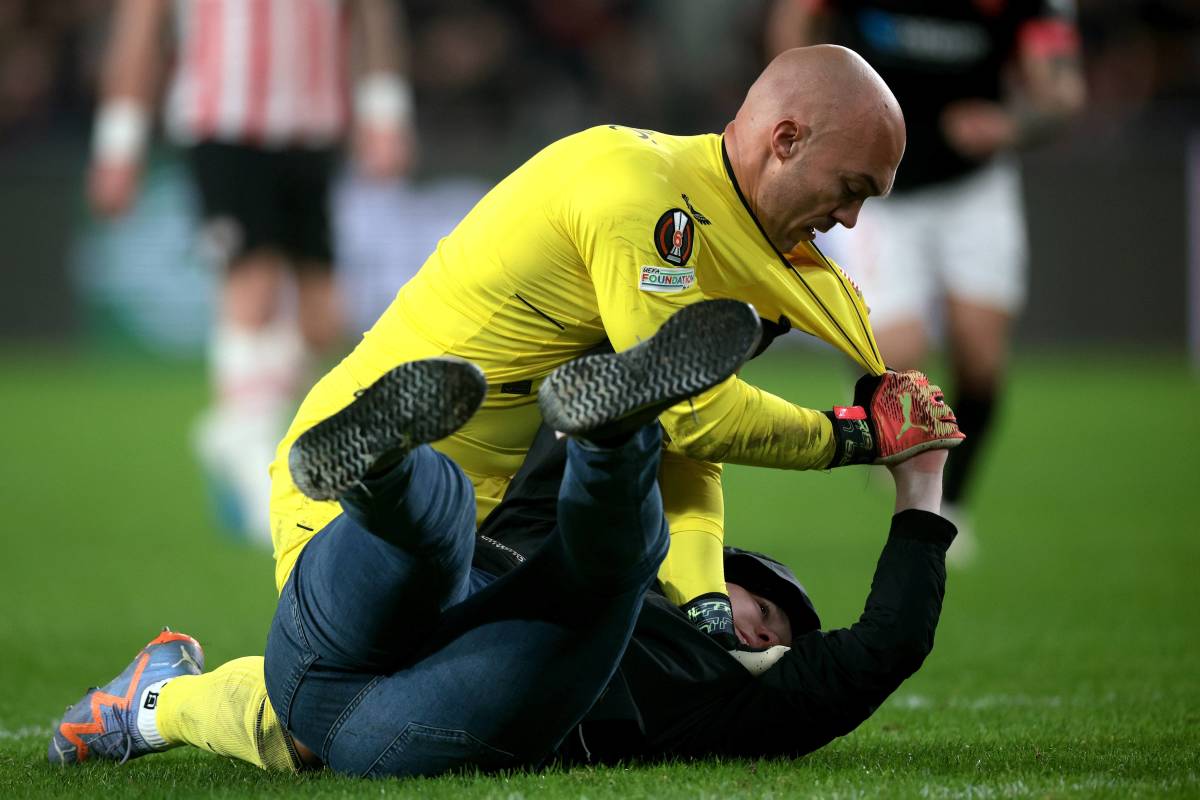Sevilla goalkeeper Marko Dmitrovic pictured grappling with a PSV Eindhoven fan who ran onto the field and tried to attack him in February 2023