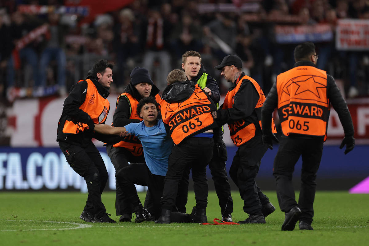 A pitch invader pictured being restrained by security after trying to grab Lionel Messi following a Champions League game between Bayern Munich and PSG in March 2023