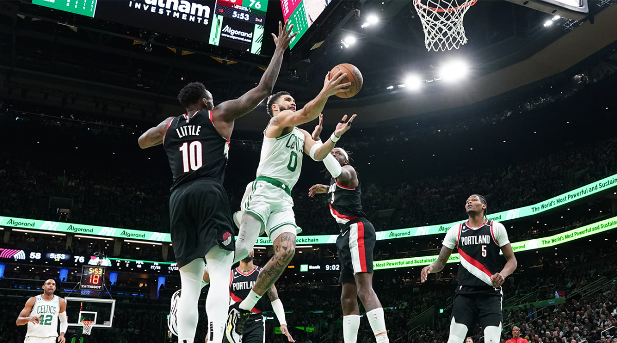 Celtics’ Jayson Tatum shoots a layup in between Trail Blazers defenders.