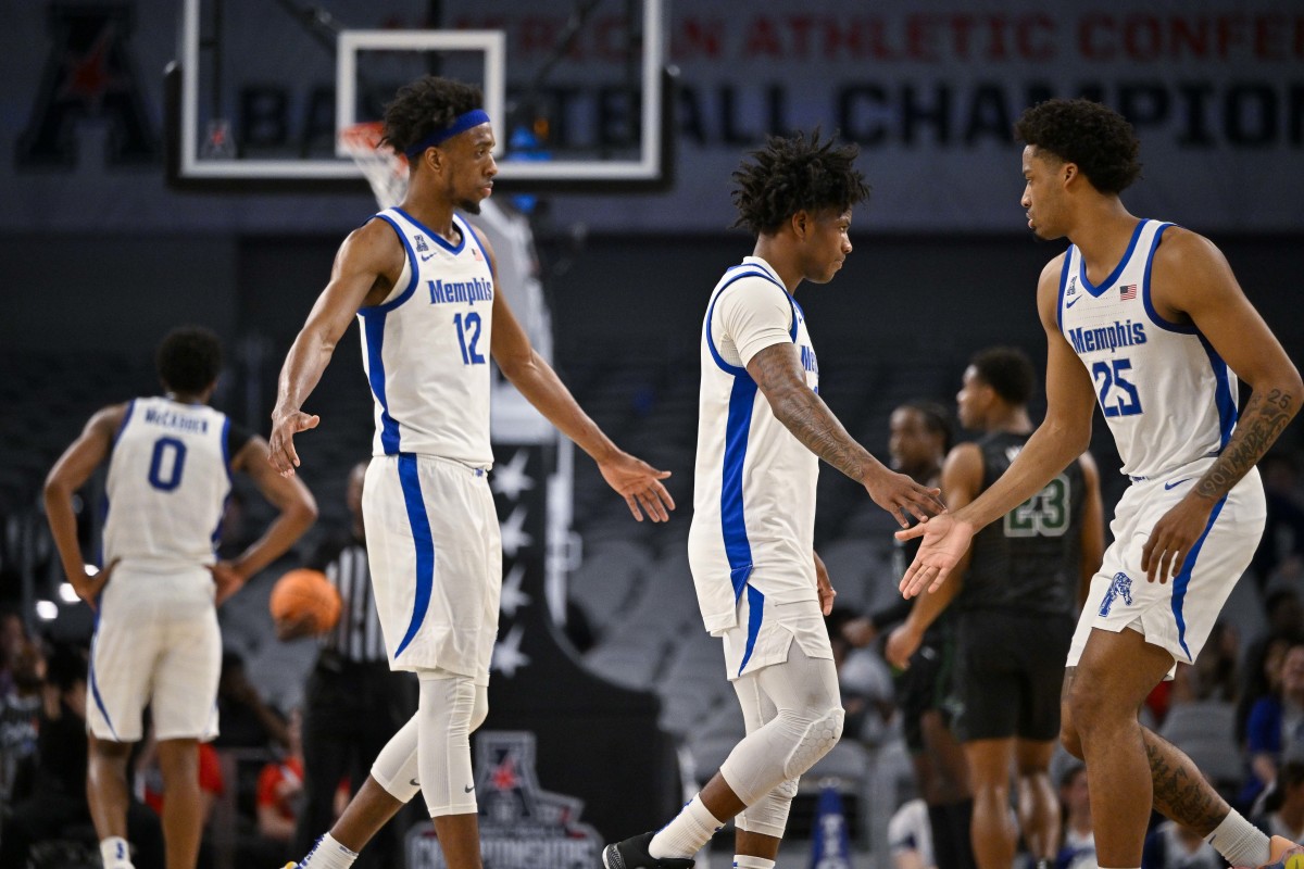 Memphis Tigers forward DeAndre Williams and guard Kendric Davis walk off the court as guard Jayden Hardaway walks on, all three reaching out for high fives