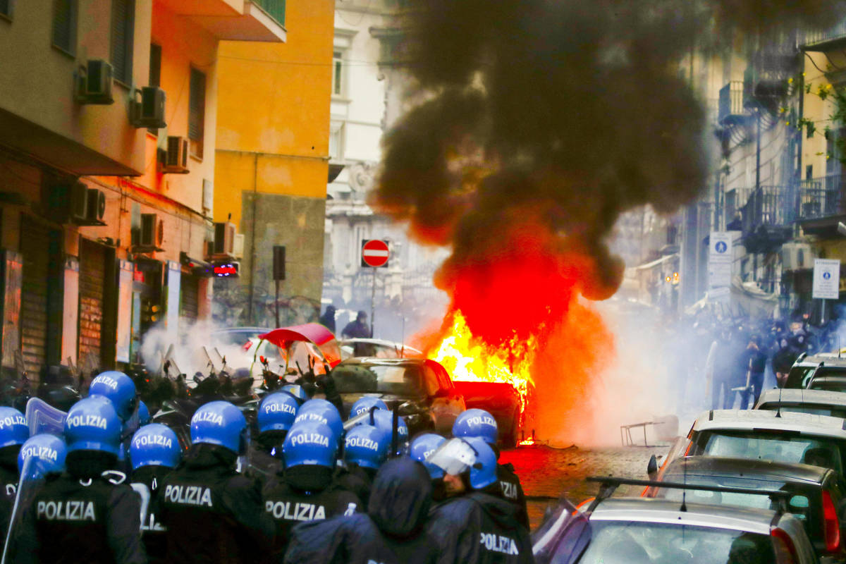 A car is pictured on fire in the city of Naples amid clashes between fans from Eintracht Frankfurt and local police in March 2023