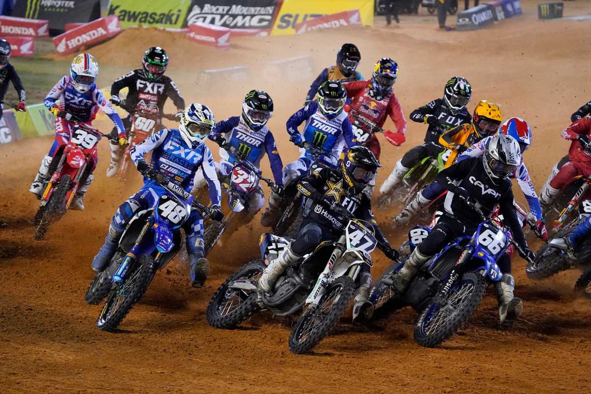 a crowd of supercross racers all next to each other on their bikes turning