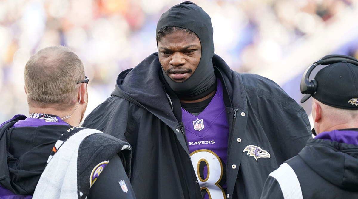 Lamar Jackson on the sideline during a game, dressed for cold weather.
