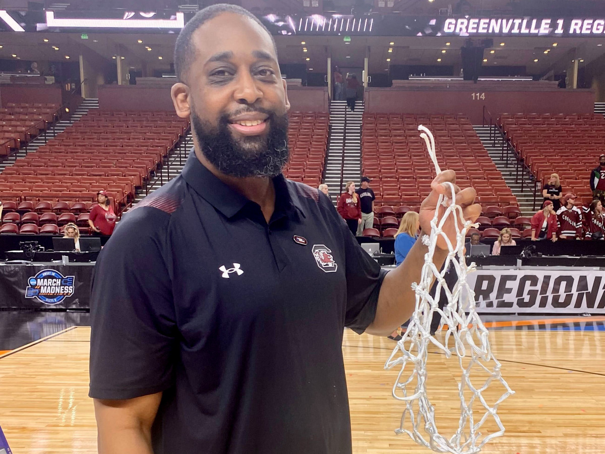 South Carolina director of player development holds up the net the Gamecocks cut down after defeating Maryland in the Elite Eight.