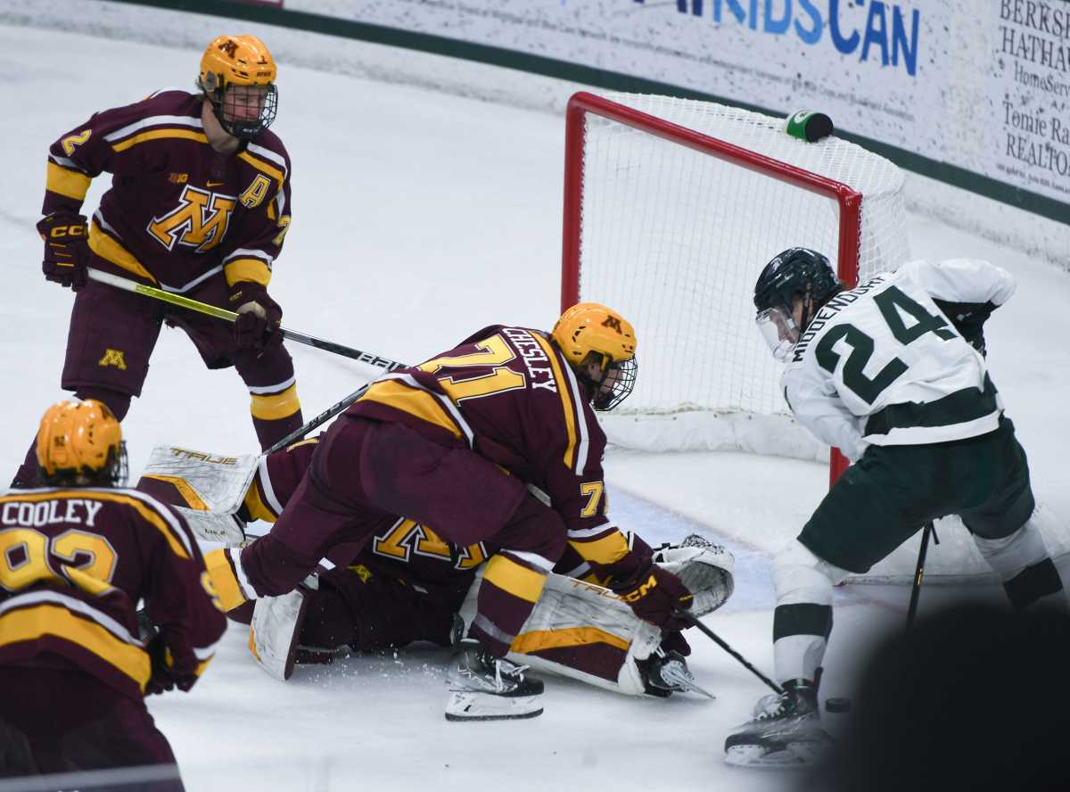 Minnesota hockey players group by the net to try to block a scorer on the other team