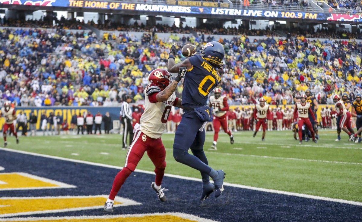 Nov 12, 2022; Morgantown, West Virginia, USA; West Virginia Mountaineers wide receiver Bryce Ford-Wheaton (0) catches a pass for a touchdown over Oklahoma Sooners defensive back Woodi Washington (0) during the third quarter at Mountaineer Field at Milan Puskar Stadium. Mandatory Credit: Ben Queen-USA TODAY Sports