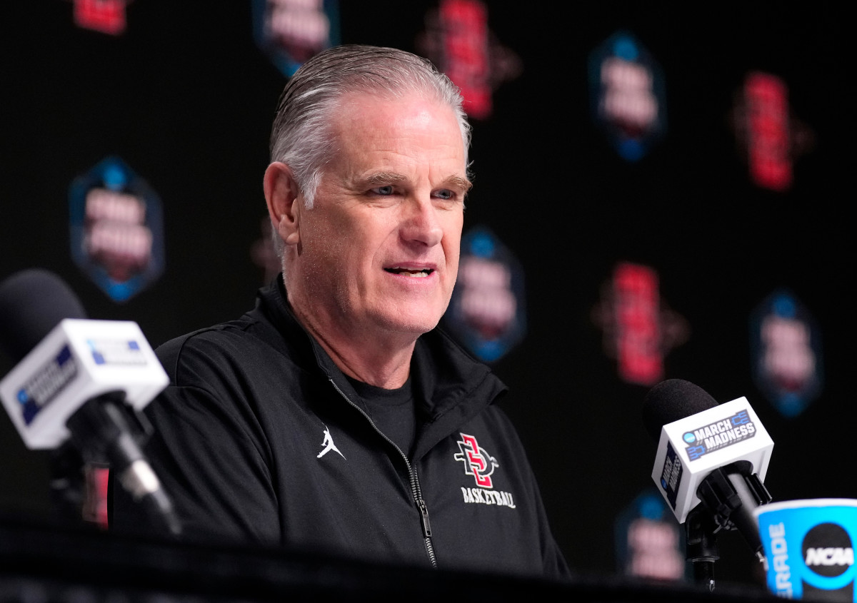 San Diego State head coach Brian Dutcher sits in front of a March-Madness-branded mic