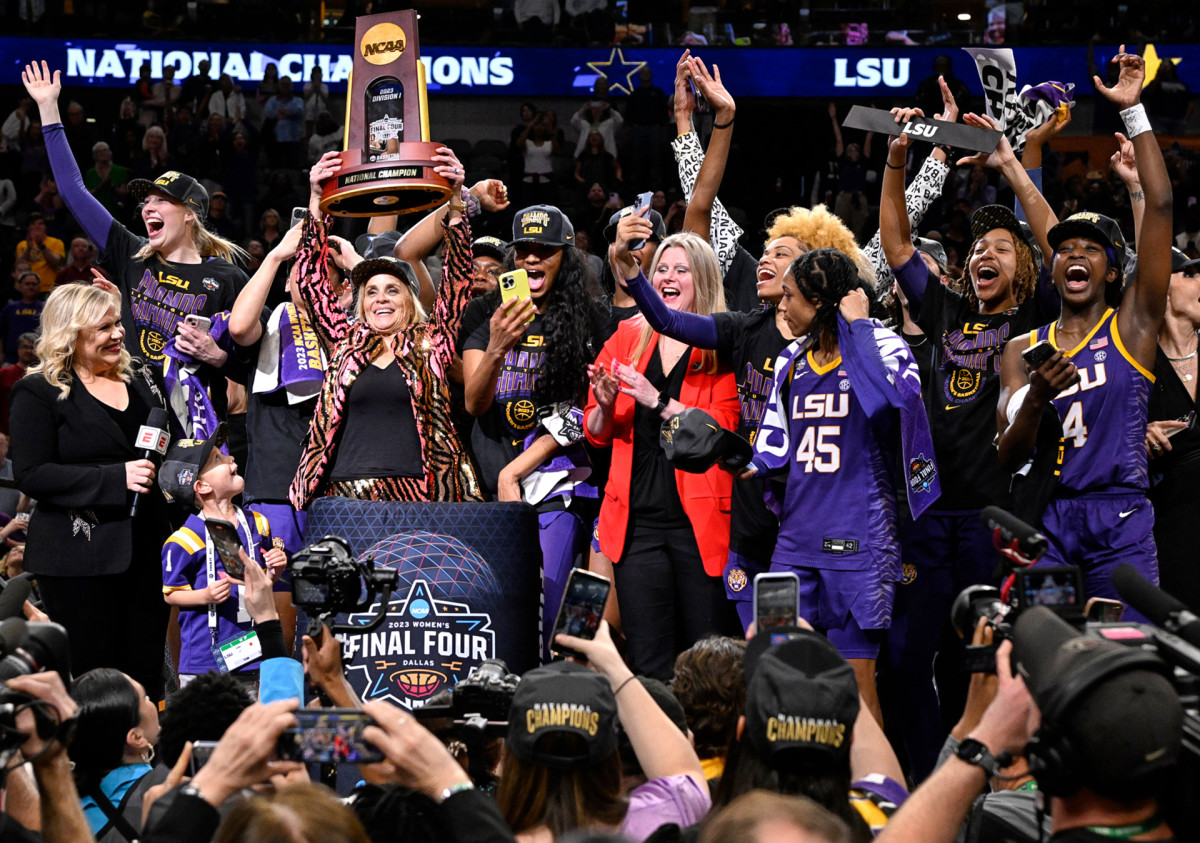 LSU coach Kim Mulkey holds up the NCAA championship trophy while the Tigers celebrate their title win.