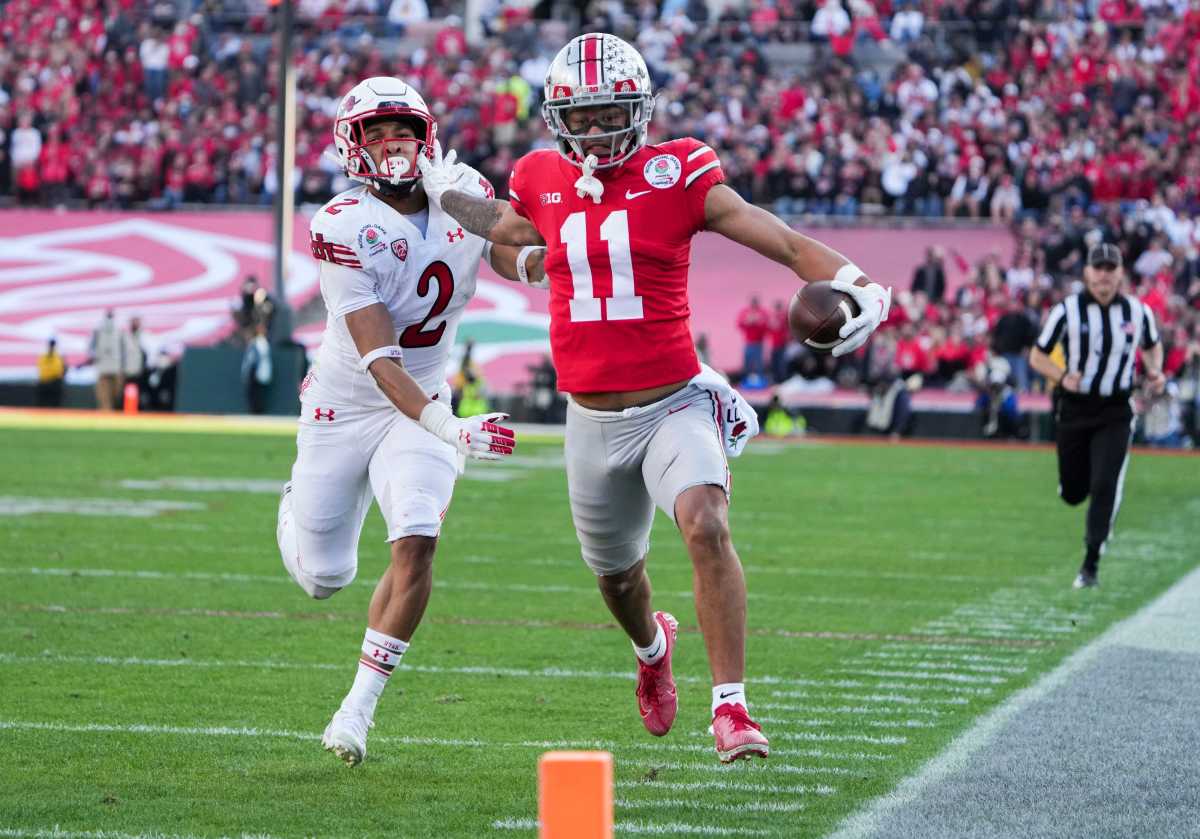 Ohio State wide receiver Jaxon Smith-Njigba runs with the football and his hand out to fend off a defender